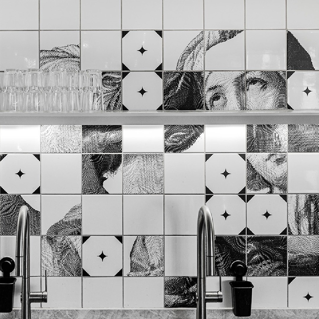 Tile wall detail — halftone portraits and star motifs broken across the kitchen grid.